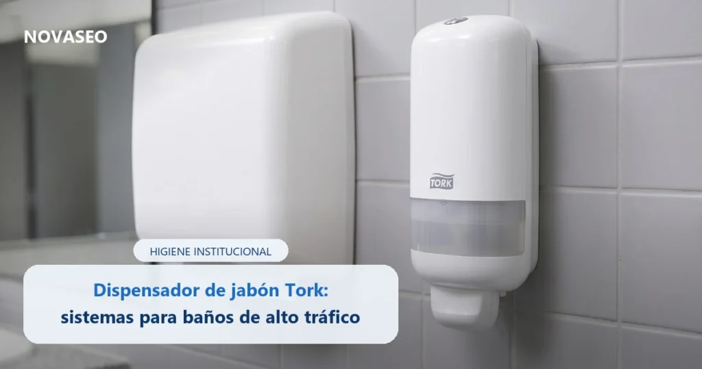 Dispensador de jabón en espuma Tork instalado en la pared de un baño institucional junto a un dispensador de toallas de papel