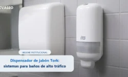 Dispensador de jabón en espuma Tork instalado en la pared de un baño institucional junto a un dispensador de toallas de papel
